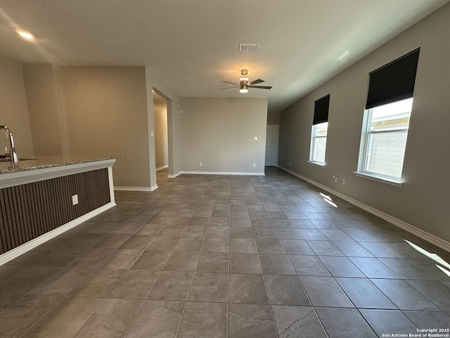 unfurnished living room featuring ceiling fan and sink