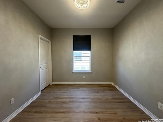 unfurnished room featuring light hardwood / wood-style floors and a chandelier