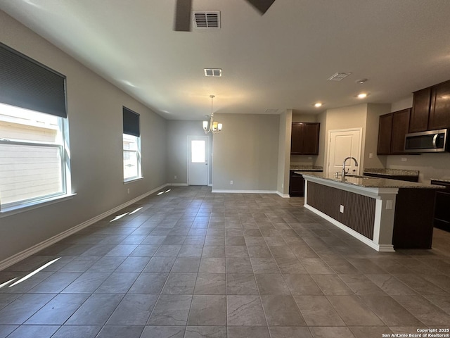 kitchen with a center island with sink, dishwasher, hanging light fixtures, a chandelier, and dark brown cabinetry