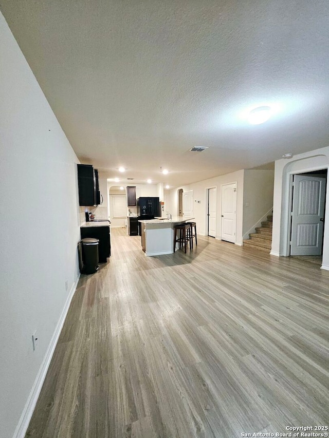 unfurnished living room with a textured ceiling and light hardwood / wood-style flooring