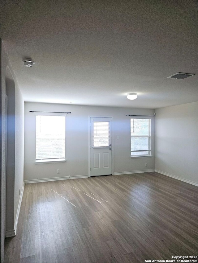 unfurnished room with hardwood / wood-style floors and a textured ceiling