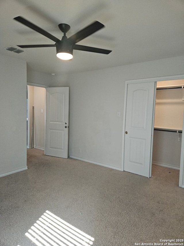 unfurnished bedroom with ceiling fan, light colored carpet, a closet, and a walk in closet