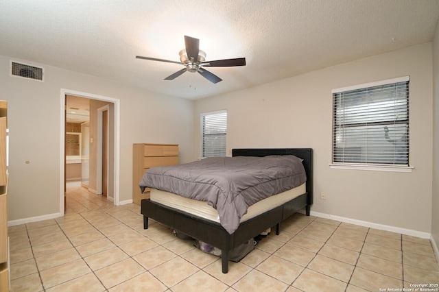 tiled bedroom with a textured ceiling, ceiling fan, and connected bathroom