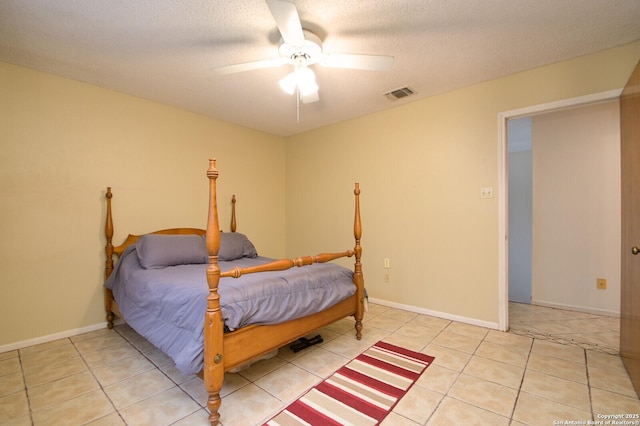 bedroom with ceiling fan, light tile patterned floors, and a textured ceiling