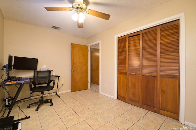 tiled office space with a textured ceiling and ceiling fan