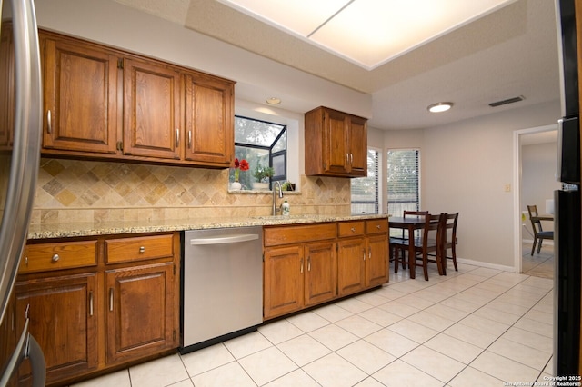 kitchen featuring decorative backsplash, sink, stainless steel dishwasher, and light tile patterned floors