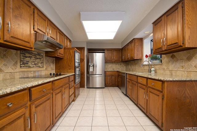 kitchen featuring light stone countertops, decorative backsplash, appliances with stainless steel finishes, and sink