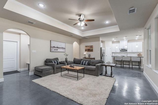 living room featuring crown molding, ceiling fan, and a tray ceiling