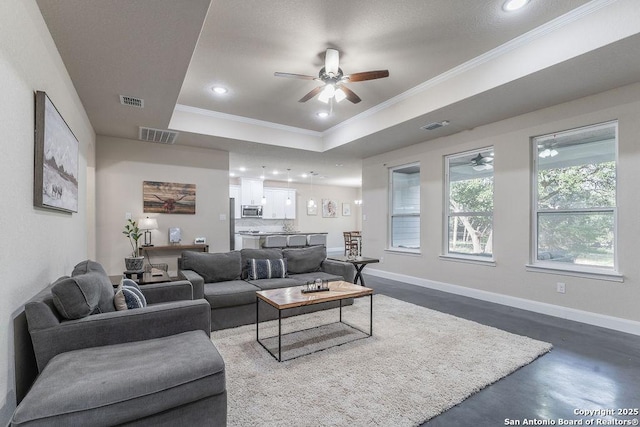 living room featuring a raised ceiling, ceiling fan, concrete floors, and ornamental molding