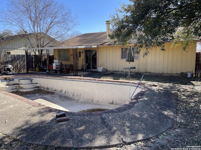 rear view of house with an empty pool