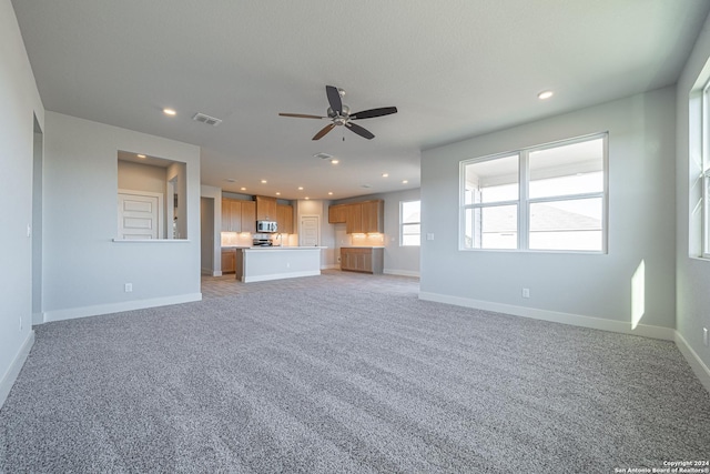 unfurnished living room with ceiling fan and light colored carpet