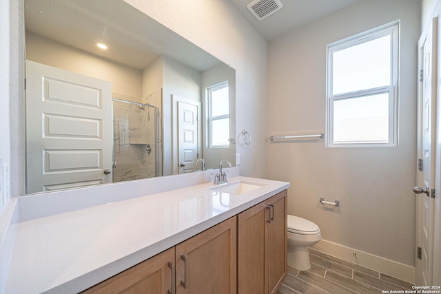 bathroom featuring plenty of natural light, an enclosed shower, vanity, and toilet