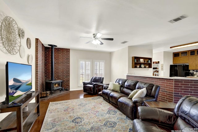 living room featuring ceiling fan, a wood stove, and dark hardwood / wood-style flooring