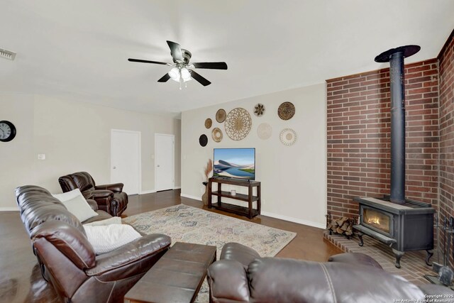 living room with ceiling fan, dark hardwood / wood-style floors, and a wood stove