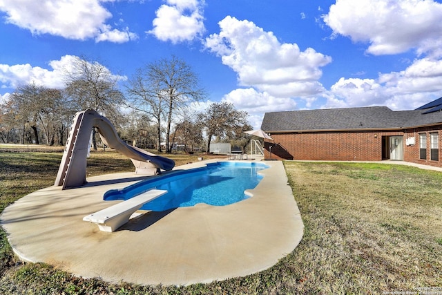 view of pool with a diving board, a water slide, and a yard