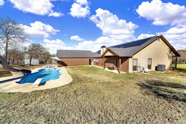 rear view of property featuring a lawn, cooling unit, a patio area, and solar panels