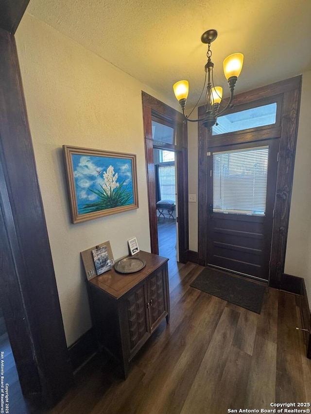 entrance foyer with a textured ceiling, dark hardwood / wood-style flooring, and a notable chandelier