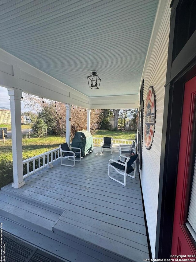 wooden deck with a grill and covered porch