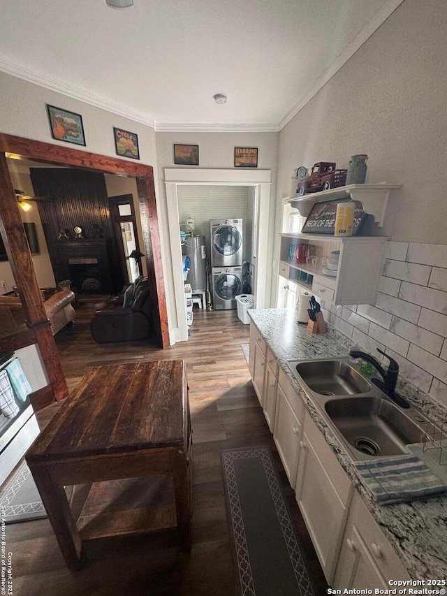 kitchen featuring sink, stacked washer and dryer, ornamental molding, dark hardwood / wood-style flooring, and light stone counters