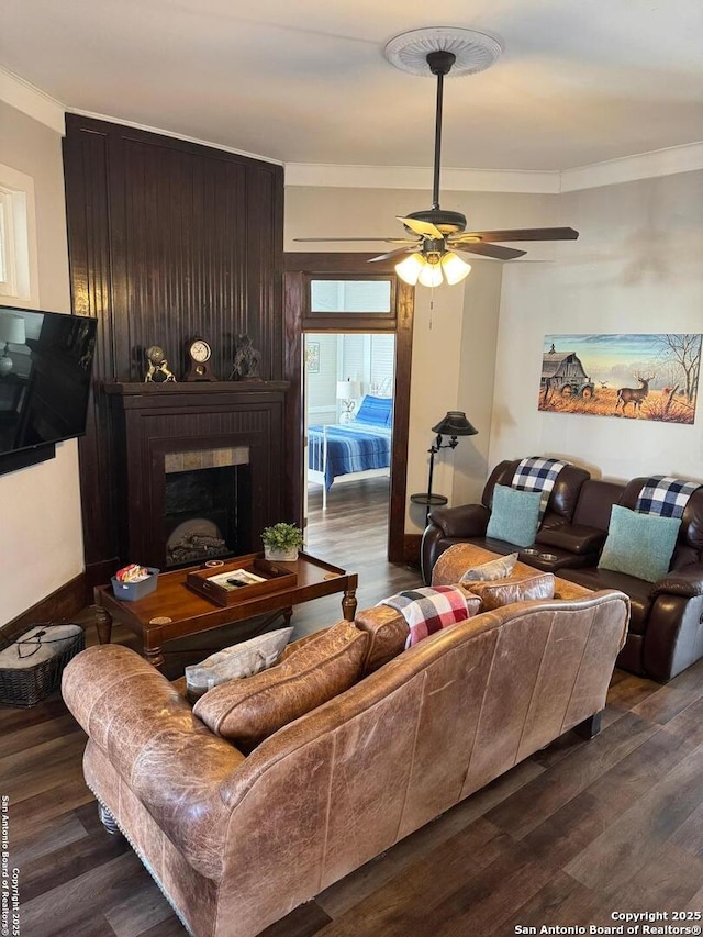 living room featuring ceiling fan, ornamental molding, a fireplace, and hardwood / wood-style floors