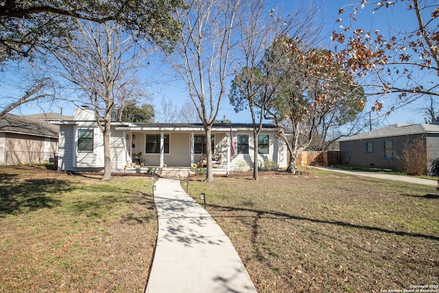 ranch-style house featuring a front yard, covered porch, and fence