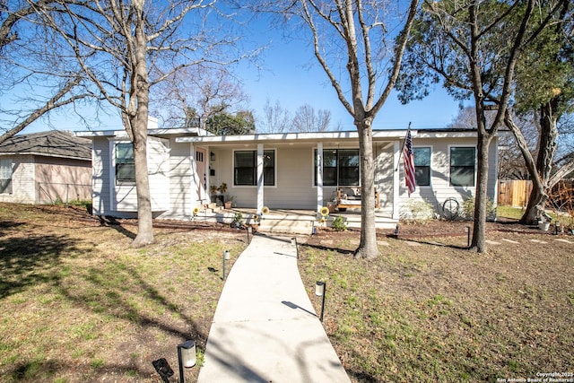 ranch-style house featuring a front yard, covered porch, and fence