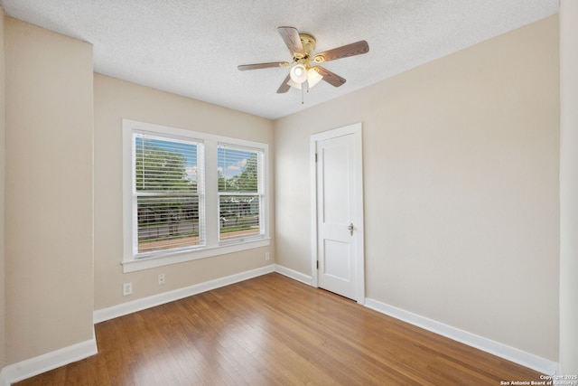 empty room featuring a textured ceiling, baseboards, ceiling fan, and wood finished floors