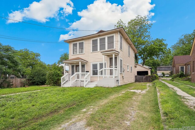 view of front of home featuring fence, a detached garage, and a front lawn