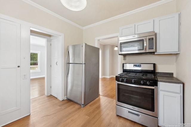 kitchen with ornamental molding, light wood finished floors, dark countertops, and stainless steel appliances