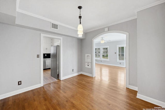 unfurnished room featuring visible vents, a ceiling fan, baseboards, light wood-type flooring, and arched walkways