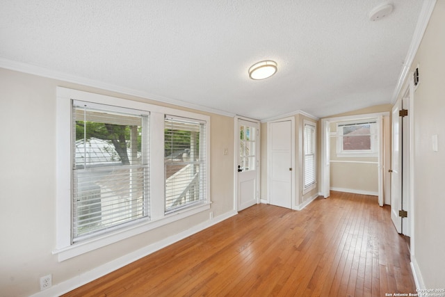 entrance foyer featuring a textured ceiling, crown molding, baseboards, lofted ceiling, and light wood-style flooring