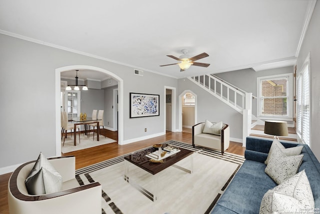 living room with stairway, arched walkways, wood finished floors, and visible vents