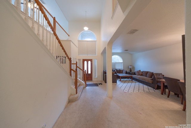 carpeted foyer entrance with a towering ceiling