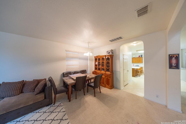 carpeted dining space with an inviting chandelier