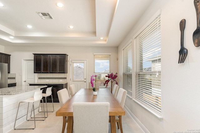 dining room with a raised ceiling and light tile patterned floors