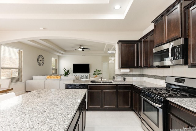 kitchen with ceiling fan, stainless steel appliances, a tray ceiling, and sink