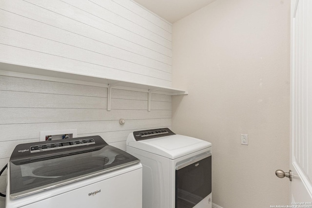 laundry area with washer and dryer and wood walls