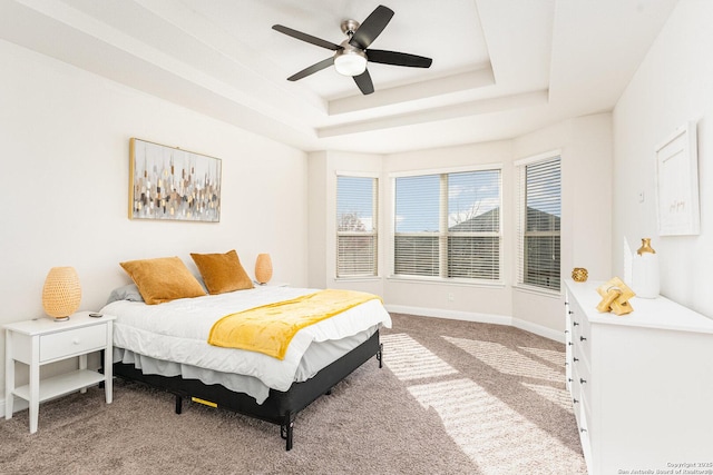 carpeted bedroom with ceiling fan and a tray ceiling