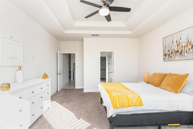 bedroom with ceiling fan, light carpet, and a raised ceiling