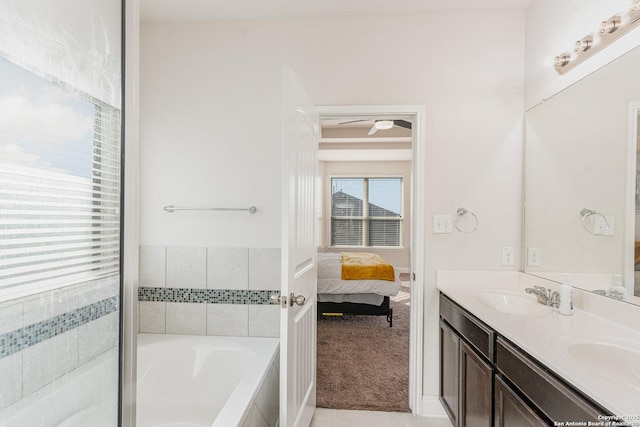 bathroom featuring ceiling fan, vanity, and a relaxing tiled tub