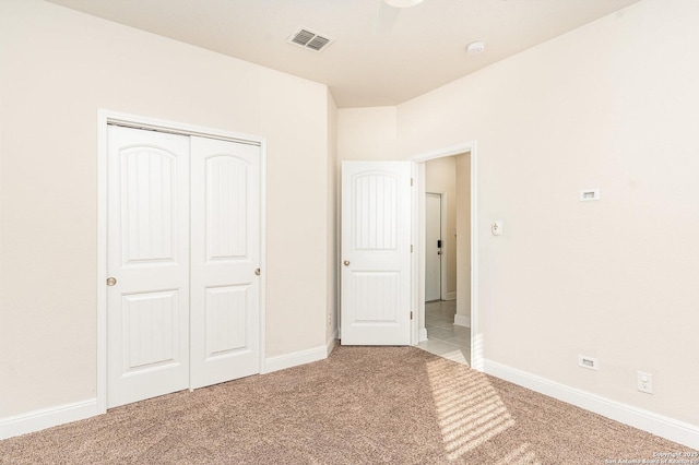 unfurnished bedroom with ceiling fan, a closet, and light carpet