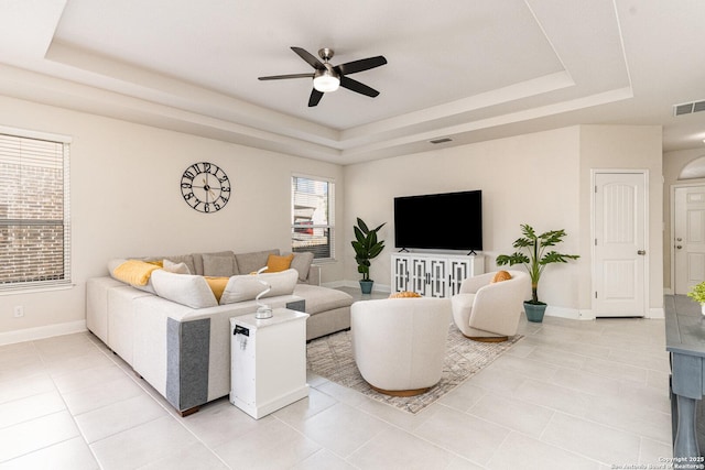 living room with ceiling fan, tile patterned floors, and a tray ceiling