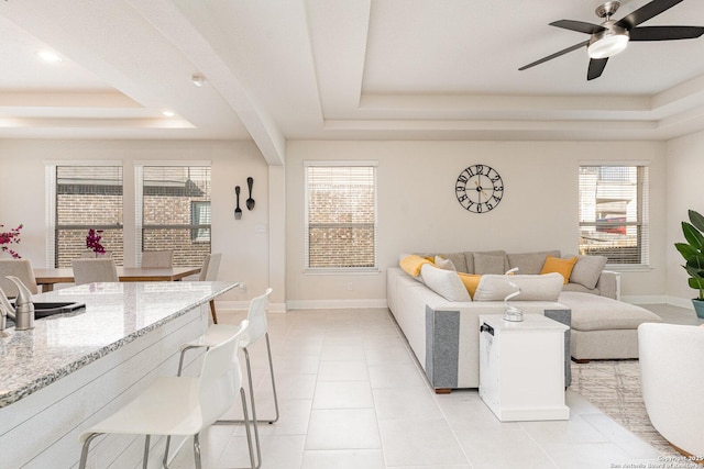 living room with ceiling fan, light tile patterned flooring, and a raised ceiling