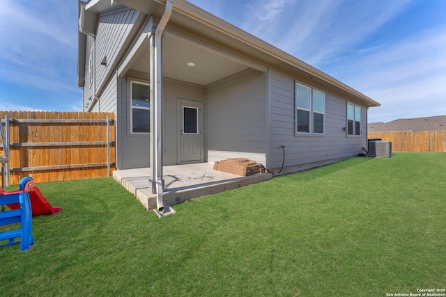 rear view of property with cooling unit, a yard, and a patio