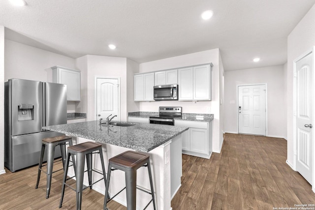 kitchen with a center island with sink, appliances with stainless steel finishes, a textured ceiling, white cabinets, and sink