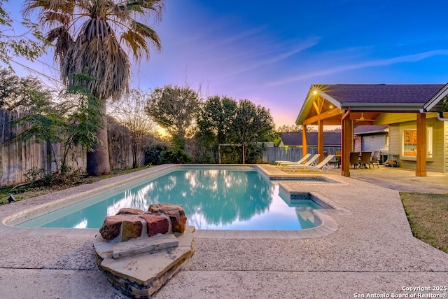 pool at dusk with a patio area and a jacuzzi