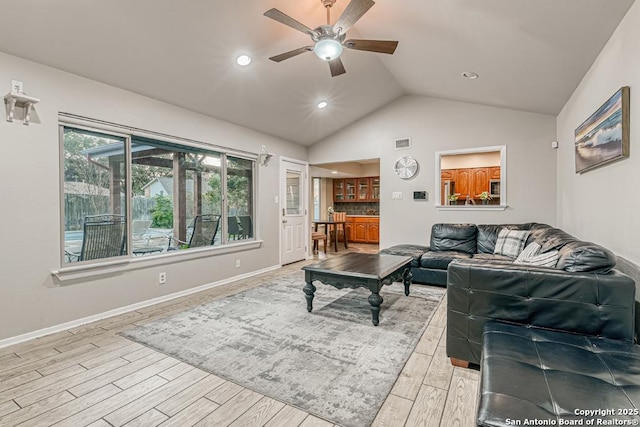 living room with ceiling fan, vaulted ceiling, and light hardwood / wood-style floors