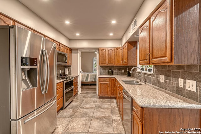 kitchen with decorative backsplash, appliances with stainless steel finishes, sink, and light stone counters