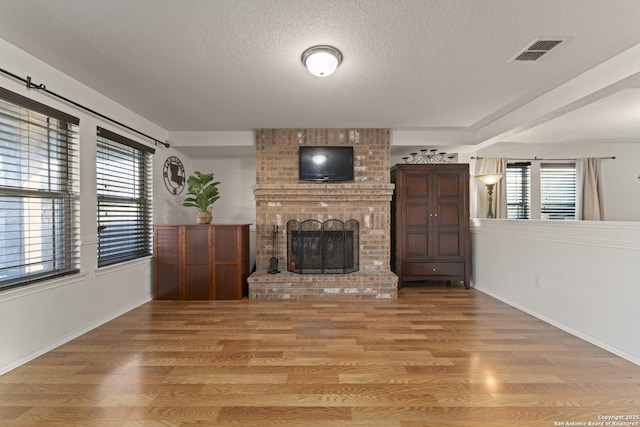 living room featuring a textured ceiling, a wealth of natural light, a fireplace, and hardwood / wood-style flooring