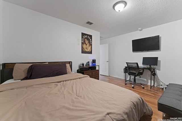 bedroom with a textured ceiling and light hardwood / wood-style floors